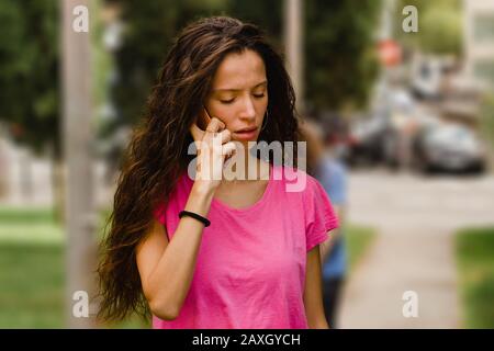 Traurige Frau auf dem Handy, Mädchen hört schlechte Nachrichten auf der Straße Stockfoto