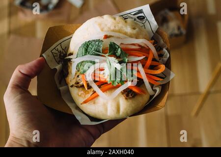 Hand halten Gua bao, hirata Bruns, bao Bruns, Guabao oder Baozi (traditionelles asiatisches Sandwich). Chinesische Küche aus Fuzhou, in Hongkong Cha bao genannt Stockfoto