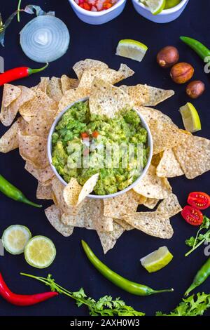 Guacamol mit allen Zutaten, authentisches mexikanisches Rezept auf schwarzem Hintergrund. Inklusive Pico de gallo (Tomate, Zwiebel und Koriander). Draufsicht Stockfoto