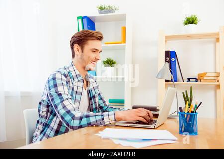 Seitenansicht junger lächelnder Arbeiter mit Laptop Stockfoto