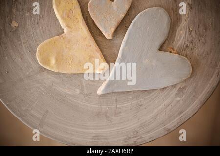 Drei mit Farben bemalte Tonherzen auf der Oberseite eines Töpferrads. Stockfoto