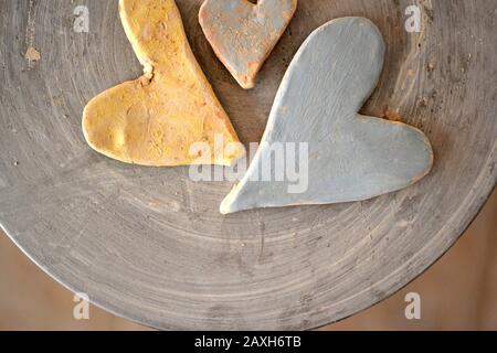 Drei mit Farben bemalte Tonherzen auf der Oberseite eines Töpferrads. Stockfoto