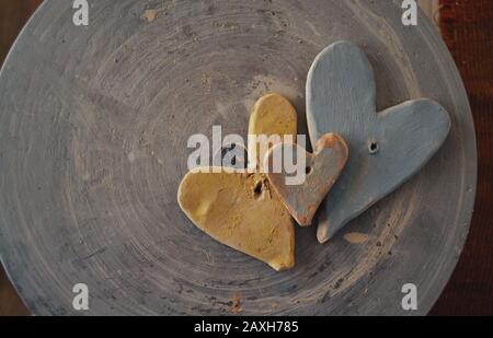 Drei mit Farben bemalte Tonherzen auf der Oberseite eines Töpferrads. Stockfoto