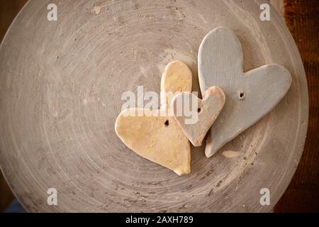 Drei mit Farben bemalte Tonherzen auf der Oberseite eines Töpferrads. Stockfoto