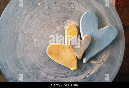 Drei mit Farben bemalte Tonherzen auf der Oberseite eines Töpferrads. Stockfoto