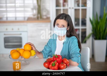 Frau, die in ihrer Küche eine medizinische Maske trägt Stockfoto