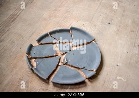 Zerbrochene Tonplatte, die auf einem Holztisch liegt Stockfoto