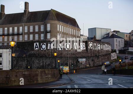 Carmarthen, Großbritannien. Februar 2020. Mitglieder des Extinction Rebellion in Carmarthen entfachen Banner, die "Act Now" ("Gweithredwch Nawr" auf walisisch) auf den Seiten der County Hall in Carmarthen lesen. Kredit: Gruffydd Ll. Thomas/Alamy Live News Stockfoto