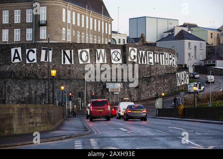 Carmarthen, Großbritannien. Februar 2020. Mitglieder des Extinction Rebellion in Carmarthen entfachen Banner, die "Act Now" ("Gweithredwch Nawr" auf walisisch) auf den Seiten der County Hall in Carmarthen lesen. Kredit: Gruffydd Ll. Thomas/Alamy Live News Stockfoto