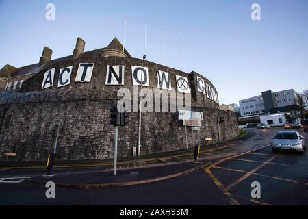 Carmarthen, Großbritannien. Februar 2020. Mitglieder des Extinction Rebellion in Carmarthen entfachen Banner, die "Act Now" ("Gweithredwch Nawr" auf walisisch) auf den Seiten der County Hall in Carmarthen lesen. Kredit: Gruffydd Ll. Thomas/Alamy Live News Stockfoto