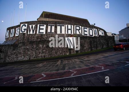 Carmarthen, Großbritannien. Februar 2020. Mitglieder des Extinction Rebellion in Carmarthen entfachen Banner, die "Act Now" ("Gweithredwch Nawr" auf walisisch) auf den Seiten der County Hall in Carmarthen lesen. Kredit: Gruffydd Ll. Thomas/Alamy Live News Stockfoto