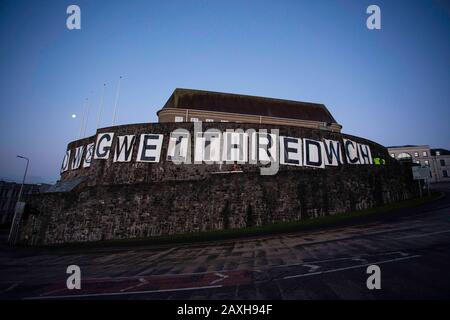 Carmarthen, Großbritannien. Februar 2020. Mitglieder des Extinction Rebellion in Carmarthen entfachen Banner, die "Act Now" ("Gweithredwch Nawr" auf walisisch) auf den Seiten der County Hall in Carmarthen lesen. Kredit: Gruffydd Ll. Thomas/Alamy Live News Stockfoto