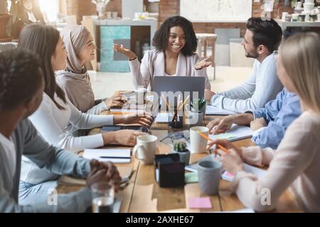 Fröhliche junge Geschäftsgruppe mit morgendlicher Unterweisung im Büro Stockfoto