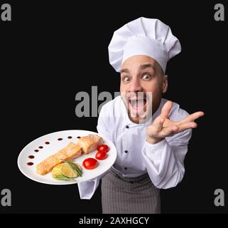 Lustiger Koch Mit Salmon-Gericht Auf Dem Teller, Studio Shot, High-Angle Stockfoto