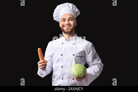 Happy Chef Mann Posiert Holding Karotte Und Kohl, Studio Erschossen Stockfoto