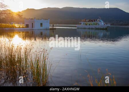 Touristenschiff in der Nähe des Fischerhauses, das über dem Banyolesee, Girona, Katalonien, Spanien gebaut wurde Stockfoto