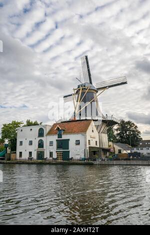 Alphen aan den Rijn, Niederlande - September 2019: Blick auf die klassische Produktionswindmühle "de Eendracht" entlang des Flusses "Oude Rijn" (Alter Rhein). Stockfoto