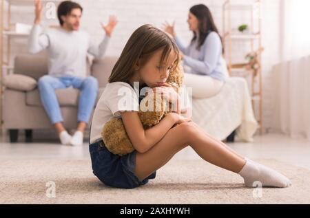 Verärgert Kleines Mädchen, Das Teddybär Knudelt Und Unter Den Eltern Leidet, Die Streiten Stockfoto