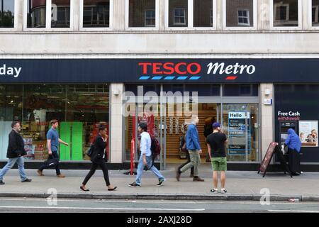 London, Großbritannien - 6. JULI 2016: People Walk by Tesco Express Lebensmittelgeschäft in London. Tesco hatte mit Stand 2017 5.500 Filialen. Stockfoto