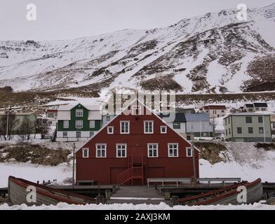 Ein rotes Holzhaus in Island vor einem schneebedeckten Berg Stockfoto