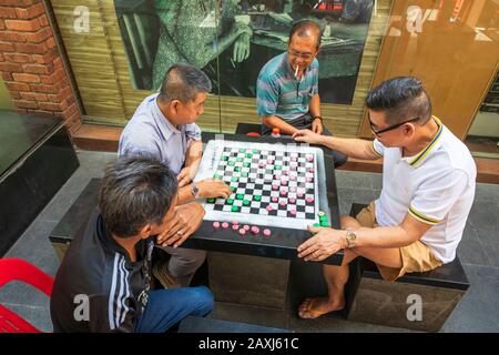 Lokale chinesische Männer spielen die lokalen und beliebten Checker aus Singapur in einer Hinterstraße von Chinatown, Singapur, Asien Stockfoto