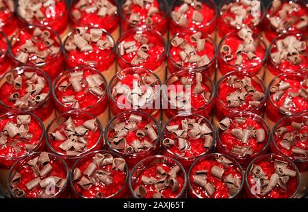 Mini-Desserts mit roter Mousse in kleinen Gläsern, mit Schokolade bestreut Stockfoto