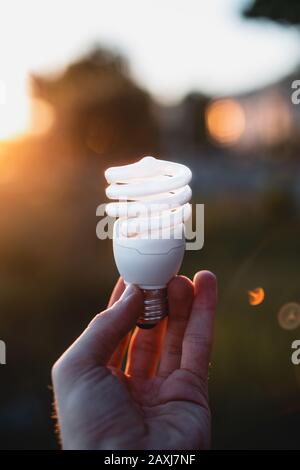 Leuchtstofflampe, die von einer Person im Freien gehalten wird. Sichtbild. Sparkonzept. Stockfoto