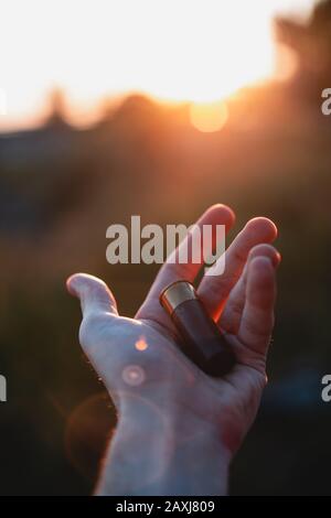 Der Mann hält eine Schrotflintekugel im Sonnenlicht, Sonnenuntergang. Jagdkonzept. Stockfoto