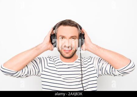 Porträt eines fröhlichen lächelnden Mannes, der Kopfhörer berührt und Musik hört Stockfoto