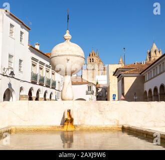 Brunnen im Largo das Portas de Moura mit Blick auf die Kathedrale und die umliegenden historischen Gebäude im Stadtzentrum von Evora, Alto Alentejo, Stockfoto