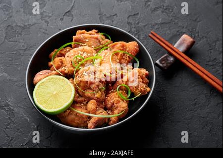 Huhn Karaage in schwarzer Schüssel mit dunklem Schieferhintergrund. Karaage ist ein traditionelles japanisches Gericht mit frittiertem mariniertem Huhn. Stockfoto