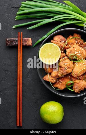 Huhn Karaage in schwarzer Schüssel mit dunklem Schieferhintergrund. Karaage ist ein traditionelles japanisches Gericht mit frittiertem mariniertem Huhn. Draufsicht Stockfoto