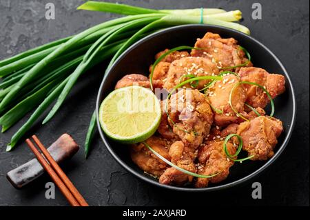 Huhn Karaage in schwarzer Schüssel mit dunklem Schieferhintergrund. Karaage ist ein traditionelles japanisches Gericht mit frittiertem mariniertem Huhn. Stockfoto