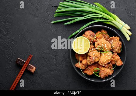 Huhn Karaage in schwarzer Schüssel mit dunklem Schieferhintergrund. Karaage ist ein traditionelles japanisches Gericht mit frittiertem mariniertem Huhn. Kopierbereich. An Stockfoto