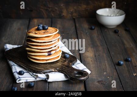 Ricotta pfannert mit Blaubeeren auf dunklem Holzhintergrund. Rustikaler Stil. Bequemes Essen. Stockfoto