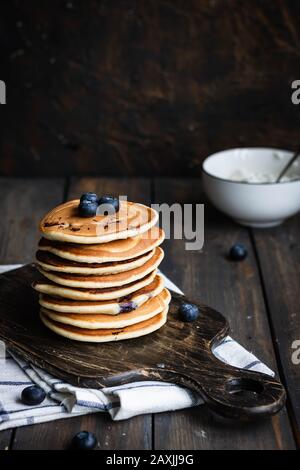 Ricotta pfannert mit Blaubeeren auf dunklem Holzhintergrund. Rustikaler Stil. Bequemes Essen. Stockfoto