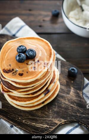 Ricotta pfannert mit Blaubeeren auf dunklem Holzhintergrund. Rustikaler Stil. Bequemes Essen. Stockfoto