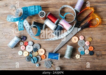 Draufsicht über Gegenstände über Nähgeräte auf Holzhintergrund. Nähkonzept und Schneiderkonzept Stockfoto