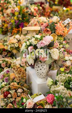 Künstliche Rosenblüten in einem Blumenladen, ein großer Blumenstrauß aus rosafarbener weißer Fake-Rose mit Blättern. Verkauf von falschen Blumensträußen von Blumen in einer Vase. Posten Stockfoto