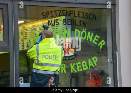 Halle, Deutschland. Februar 2020. 12. Februar 2020, Sachsen-Anhalt, Halle (Saale): Ein Gerichtsmediziner der Polizei fotografiert ein Loch in einer Fensterscheibe. Gut vier Monate nach dem Terroranschlag in Halle ist ein neues Loch im Fenster der angegriffenen Imbissbude entdeckt worden. Ob es sich um ein Einschussloch handelt, ist noch zu klären - diese Annahme bestätigte die Polizei am 12.02.2020 zunächst nicht. Ein Projektil wurde laut einem Sprecher nicht gefunden. Gerichtsmediziner sicherten sich vor Ort Beweise. Foto: Heiko Rebsch / dpa-Zentralbild / dpa Credit: Dpa Picture Alliance / Alamy Live News Stockfoto