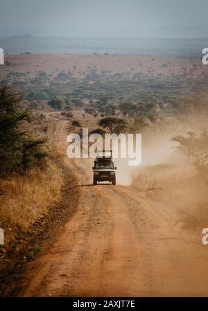 Ein Safariauto allein auf einer langen staubigen Straße durch den Serengeti, Serengeti-Nationalpark, Tansania Stockfoto