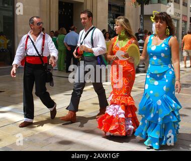 Männer und Frauen im traditionellen Kleid, die auf der Calle Marques de Larios während der Malaga-Messe in Málaga, Spanien, spazieren gehen. Stockfoto