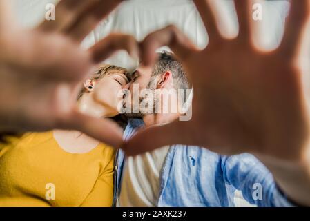 Junges romantisches Paar an einem Datum, das mit den Fingern durch eine Herzgeste küsst. Zwei schöne Paare, die gerne Zeit zusammen auf dem b verbringen Stockfoto