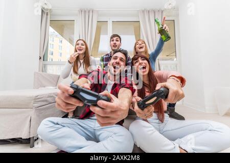 Freunde, die Videospiele spielen, haben Spaß im Wohnzimmer. Konzept für Home Entertainment. Stockfoto