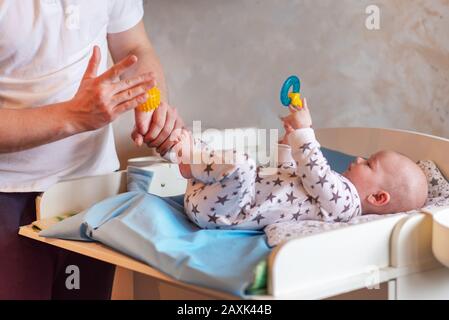 Papa gibt seinem neugeborenen Sohn eine Gummi-Kugelfußmassage Stockfoto