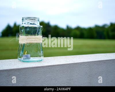 Glas-Kaffeebecher in Schnur mit Teelicht Kerze im Inneren zeigt Wiederverwendung & Recycling auf einem grünen Hintergrund mit Kopierraum gewickelt. Stockfoto