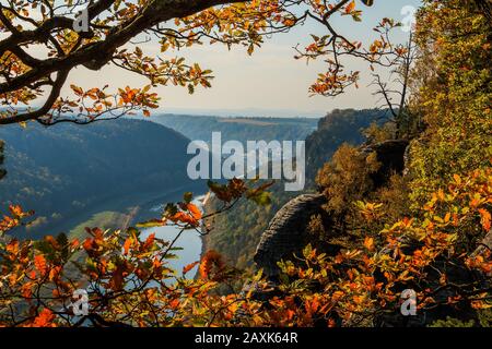 Blick über das Elbtal in der Sächsischen Schweiz an einem sonnigen Herbsttag. Felsen und Fluss Elbe mit Bäumen und Dorf im Hintergrund mit blauem Himmel Stockfoto