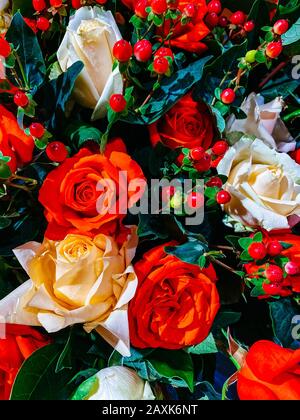 Blumenstrauß, Nahaufnahme eines Blumenstraußes, rote Rosen, Sonnenblumen, grüne Blätter. Blumenschmuck, Geschenk für den Frauentag, weddin Stockfoto