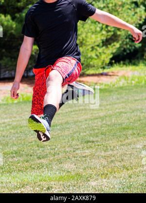 Ein High-School-Junge flieht in der Luft und übt im Leichtathletik für Weitsprung. Stockfoto