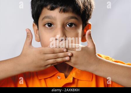 Mumbai, Maharashtra, Indien - Asien, 30. September 2006 - Concept Portrait Indian Cute Little Boy schließt seinen Mund mit den Händen. Stockfoto